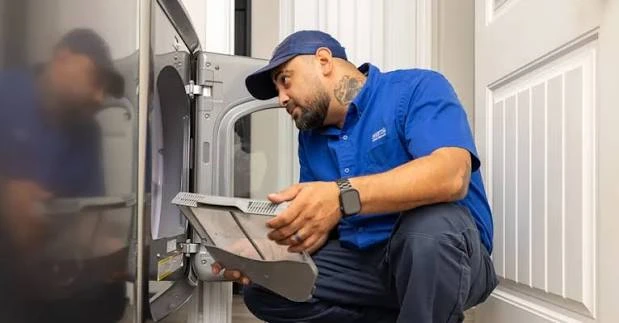 Technician examining a lint screen at an open dryer
