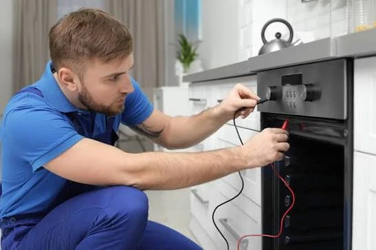 Technician checking oven controls with multimeter probes
