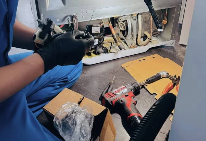 Close-up of a technician servicing refrigerator components